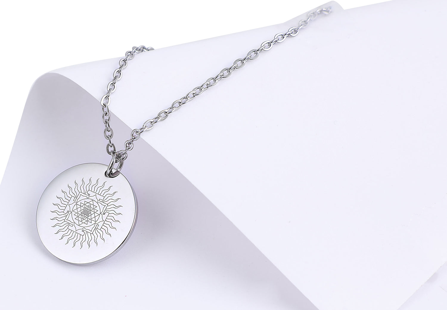 Silver necklace with a round pendant on a white background